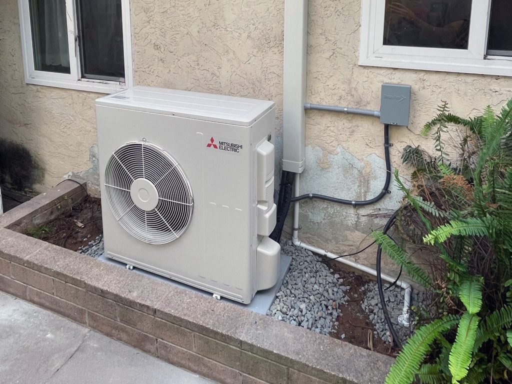 Ductless mini split outdoor condenser unit installed next to a house, featuring Mitsubishi Electric branding, showcasing energy-efficient HVAC solutions for personalized comfort in Escondido homes.
