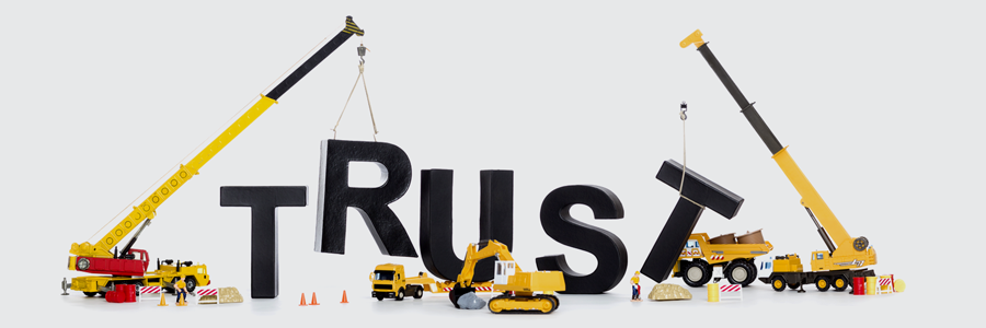 Cranes lifting the word "TRUST" with toy construction vehicles, symbolizing reliability in commercial HVAC services.