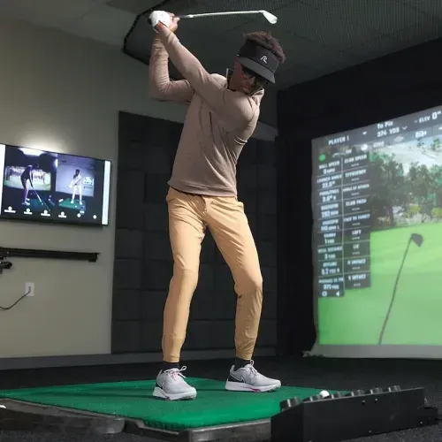 Practicing golf swing indoors at GOLFTEC center
