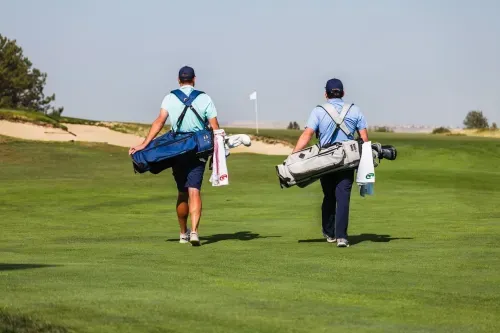 Two golfers holding their bags walking to their ball on the fairway