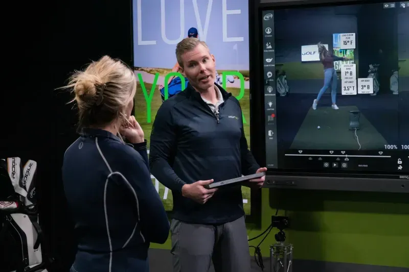 GOLFTEC coach and student reviewing OptiMotion results on screen during lesson