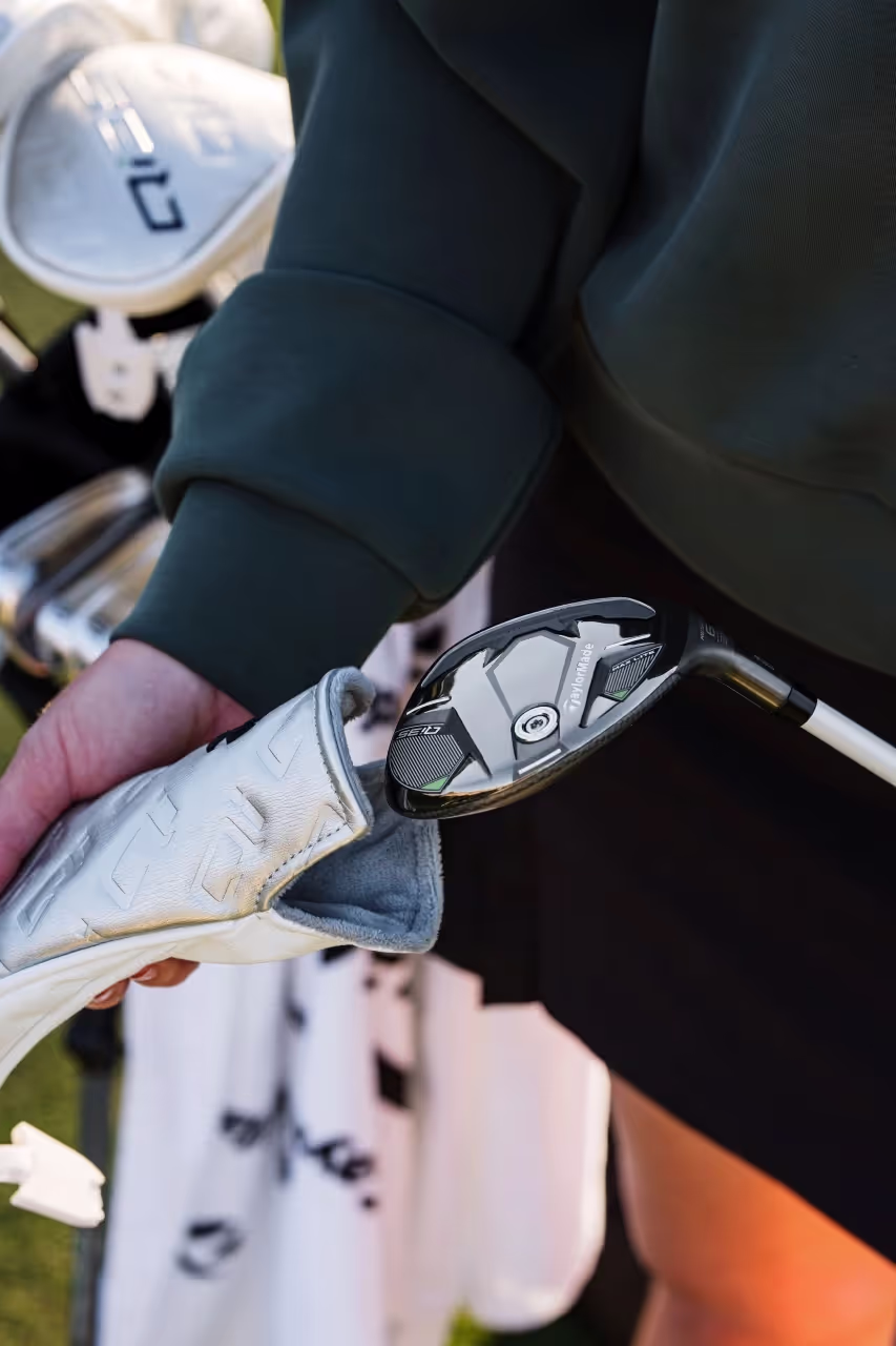 Zoomed-in view of a golfer's club bag, with a golfer wearing a green long sleeve 