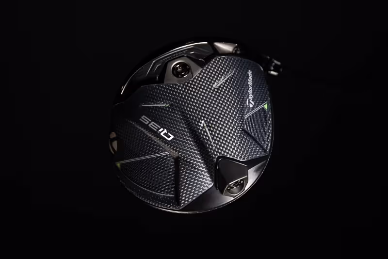 Close-up view of the bottom of a driver clubhead against a black background, emphasizing its shape, design, and details.