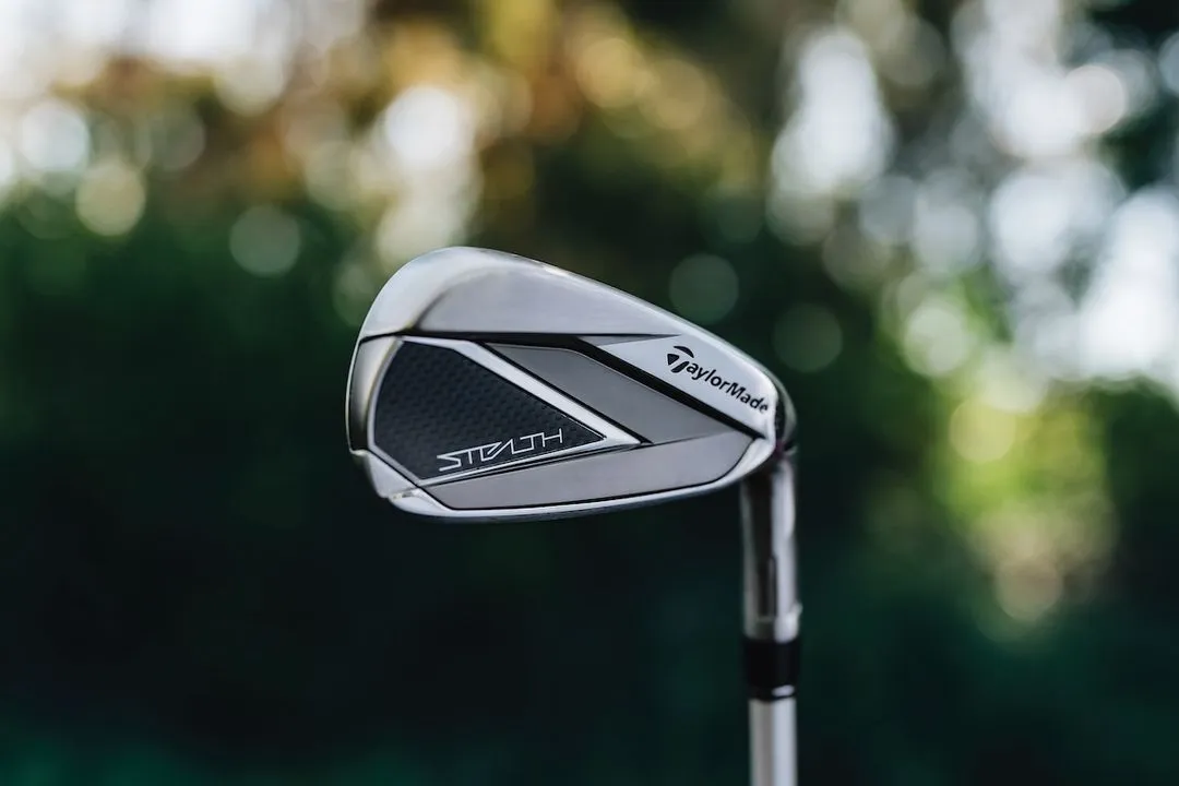 TaylorMade Stealth HD iron with a blurred tree background.