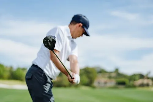 Golfer mid-backswing with a TaylorMade Qi10 Max driver with a green course in the background. 