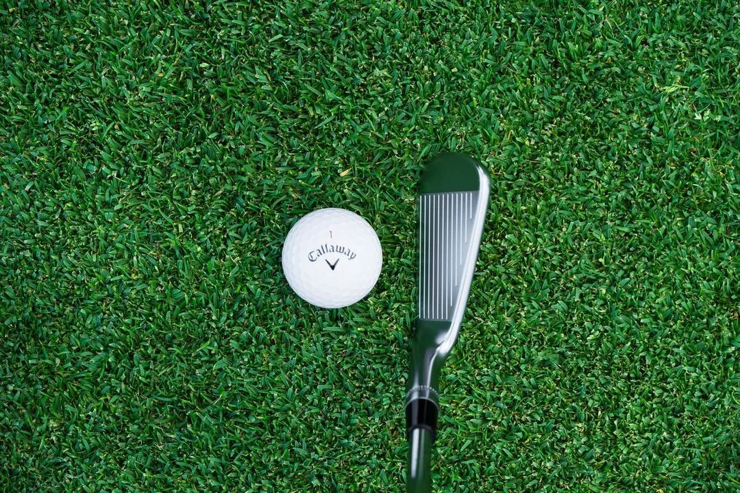 Top view of the Callaway Apex CB Iron lined up on turf, ready to hit the golf ball.