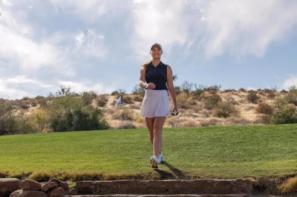 Woman golfer walking on the course holding a Scottsdale putter.