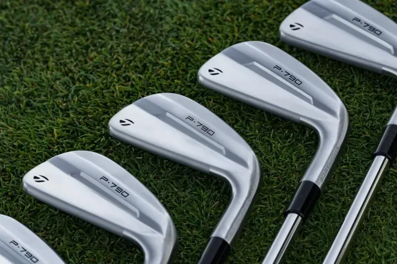 TaylorMade P970 Irons lined up on the grass, highlighting their head design. 
