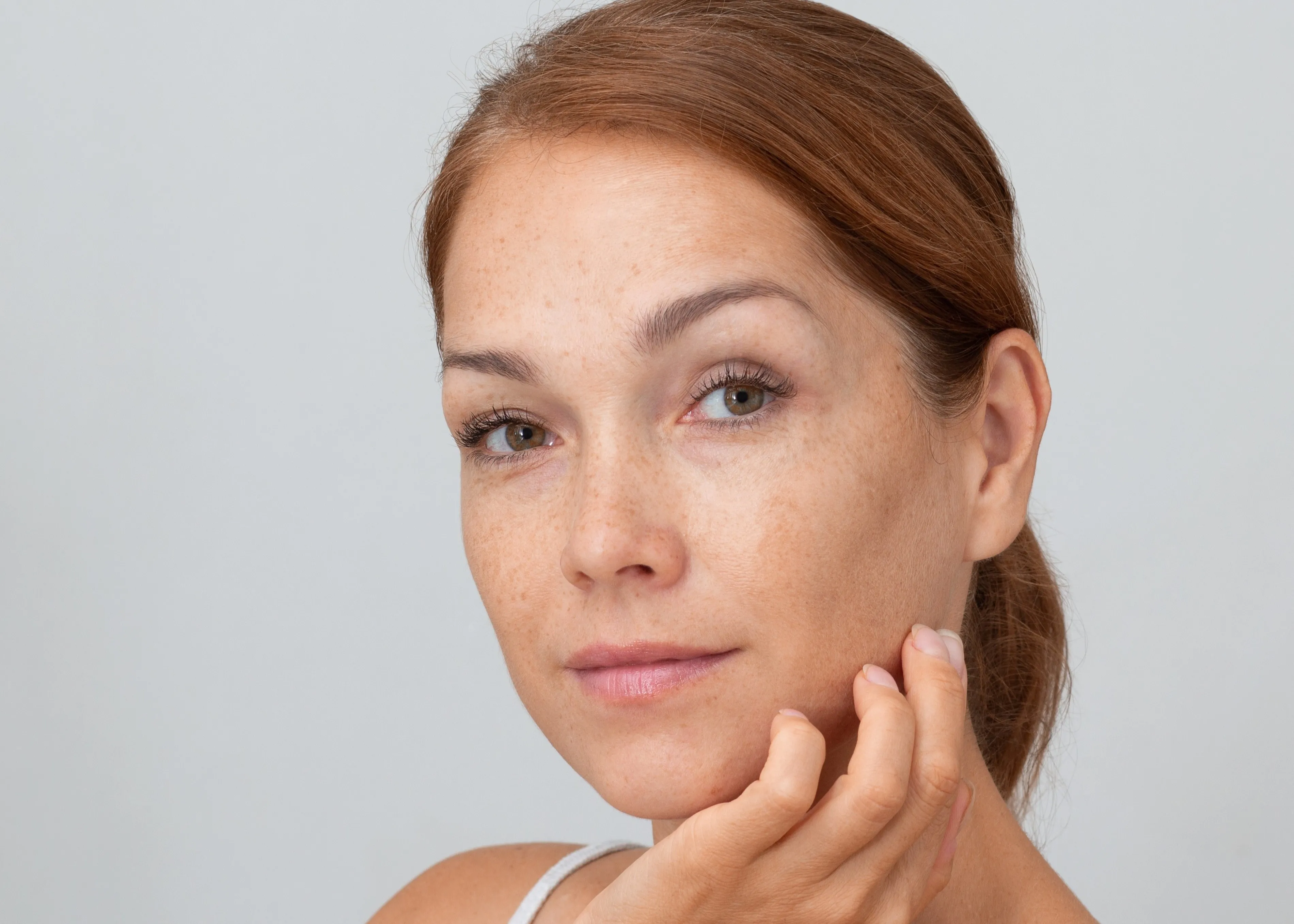 A woman with freckled hair is posing for a picture.