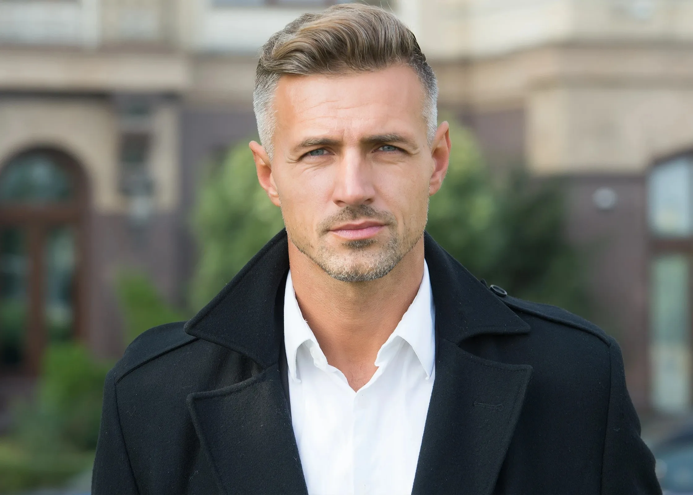 A man wearing a black coat and a white shirt.
