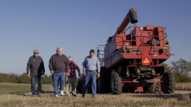 ed gallrein walking across farm land next to a large piece of farm machinery