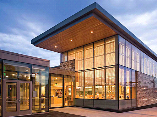 A modern glass library building lit from within