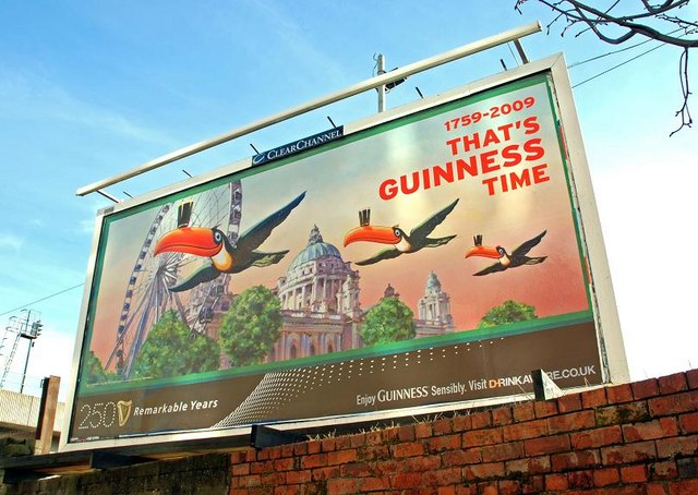 Guinness billboard from 2009 showing an illustration of three toucans flying with beer glasses balanced on their beaks.