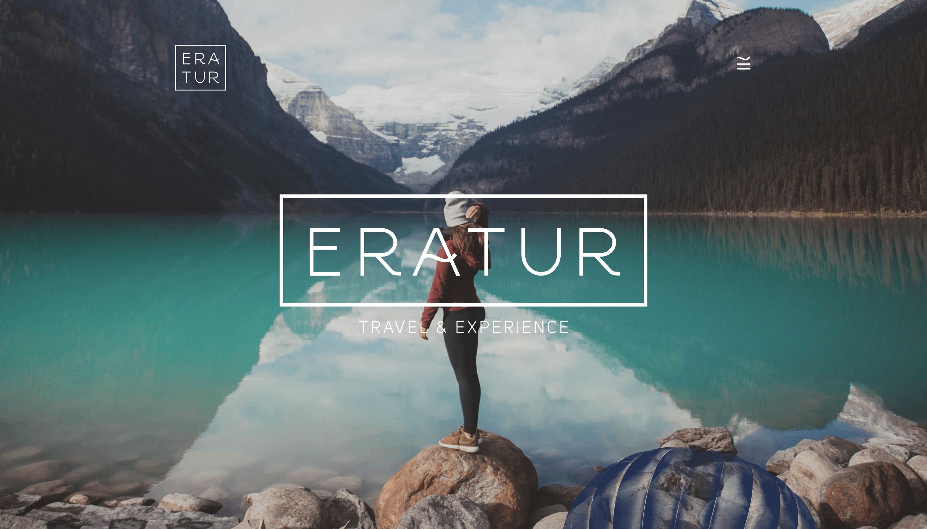 A screenshot of Eratur’s website showcasing an image of a person standing on a rock looking out at turquoise water surrounded by mountains.