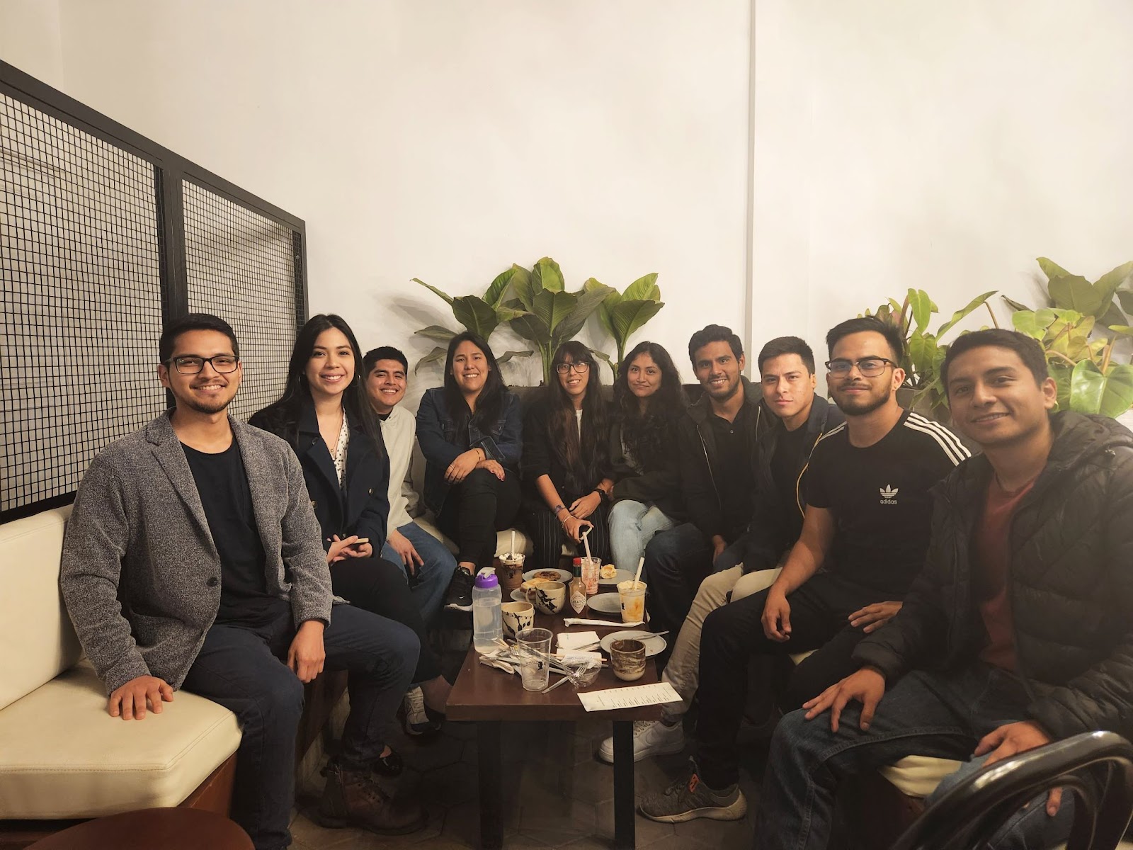 A group of Webflow community members sit in front of plants and a window.