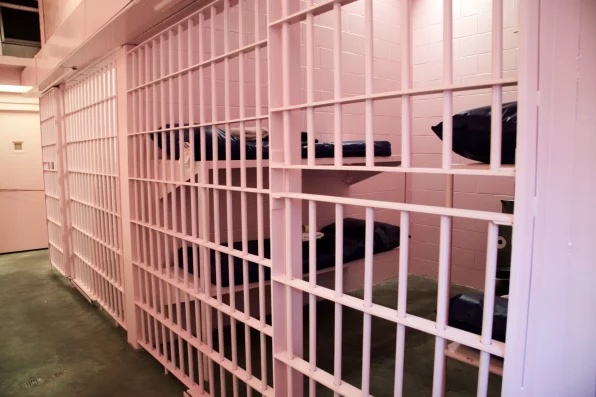 A photo of a pink painted empty jail cell