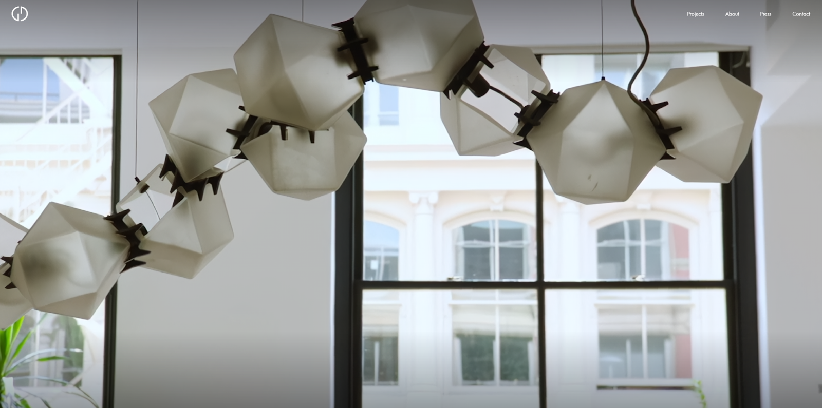 The Gramercy Design homepage begins with an image of a chandelier made of a curved line of polygonal fixtures.