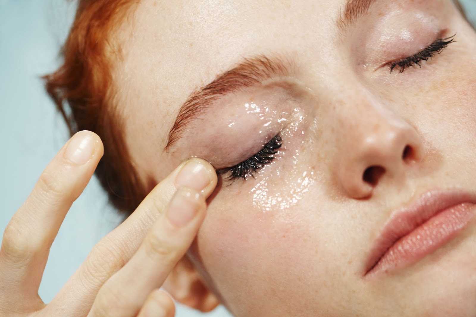 An advertisement for Milky Jelly Cleanser from Glossier. It features a woman wiping the cleanser on her face.