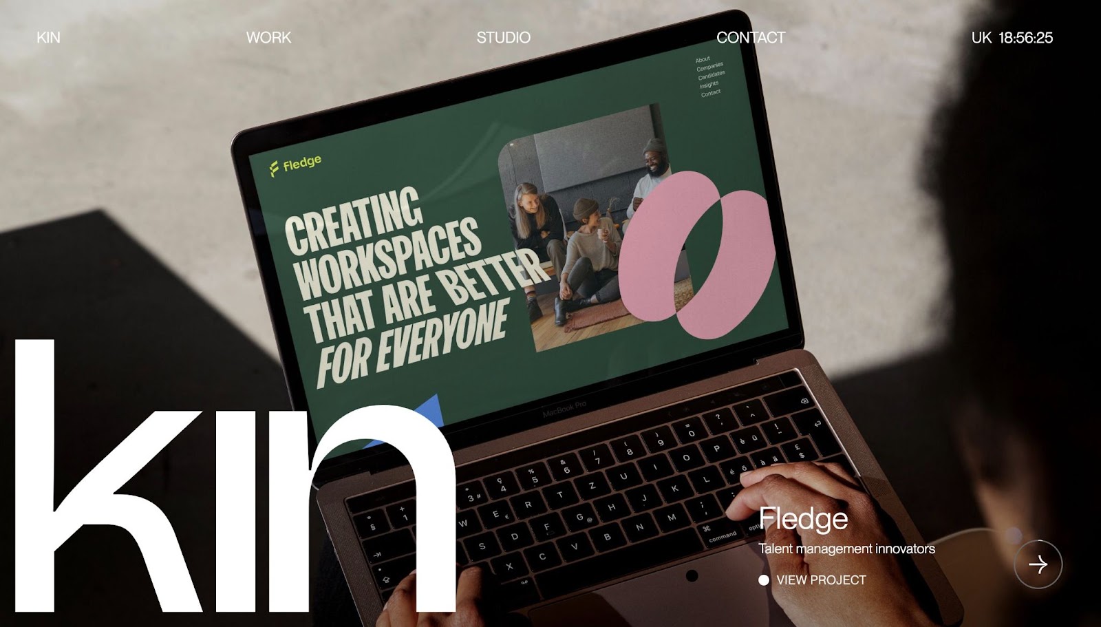 An image of the Kin wbsite. It features the word "kin" in oversized font overlayed over an image of someone on a laptop.