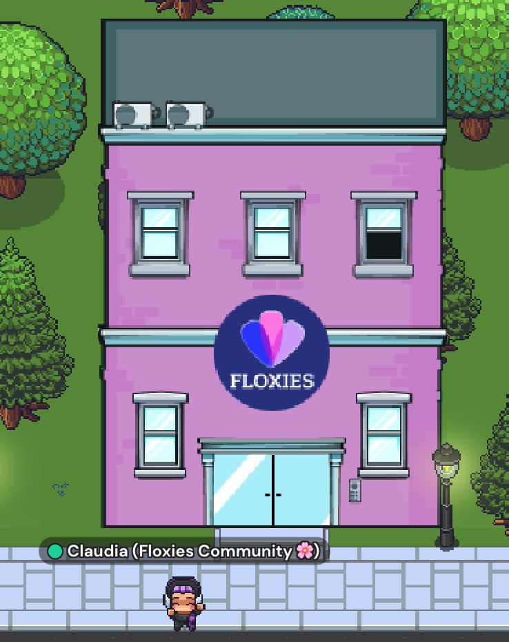 An image of the Floxies Club house in Gatherround. The Digital Club House is pink with the Floxies logo in the front. Around it are green trees and a lawn.