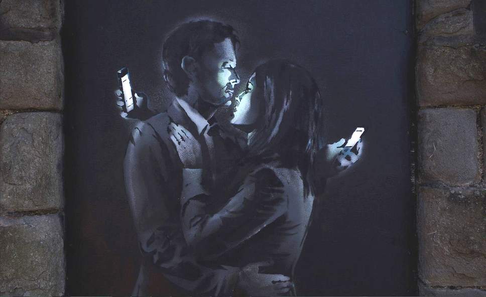 Banksy piece of a man and a woman embracing while looking at their mobile phones.