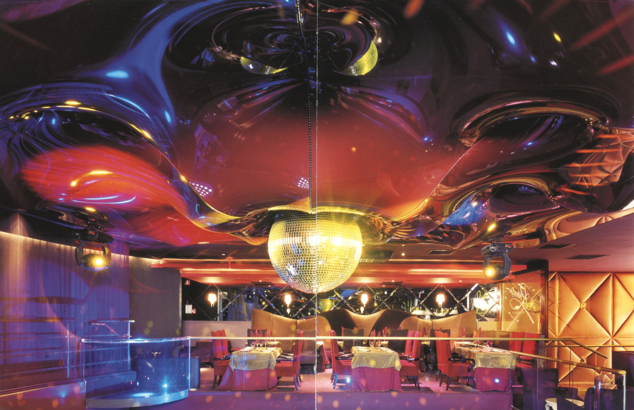 Chrmatic imagery of a room with a large centered disco ball, velvet and dining tables.