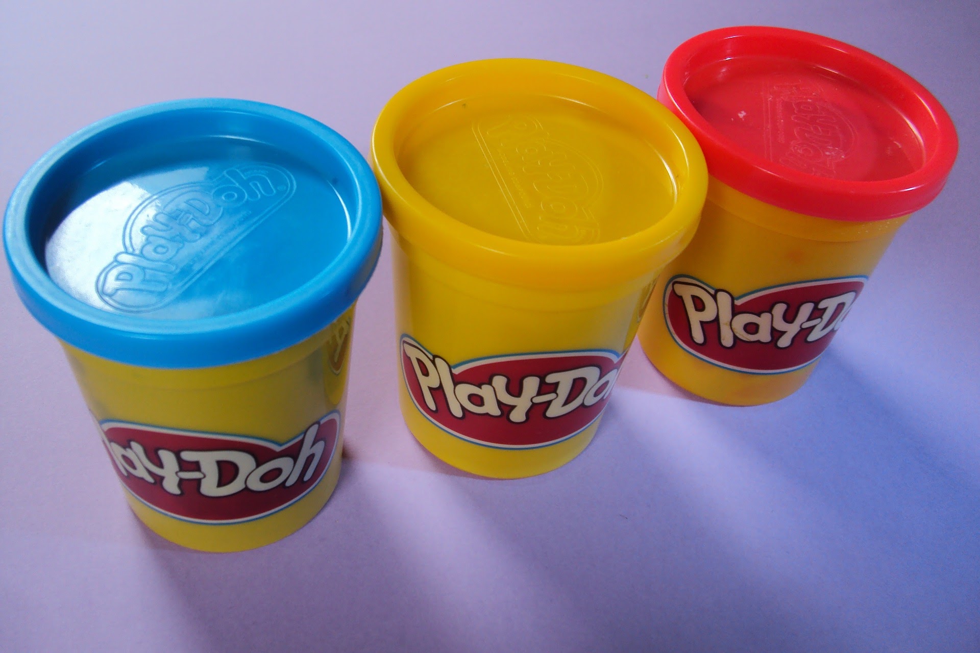 An image of blue, yellow, and red Play-Doh containers.