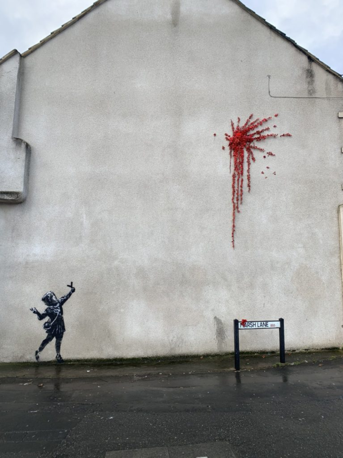 An image of a banksy mural that uses white space on the side of the building.