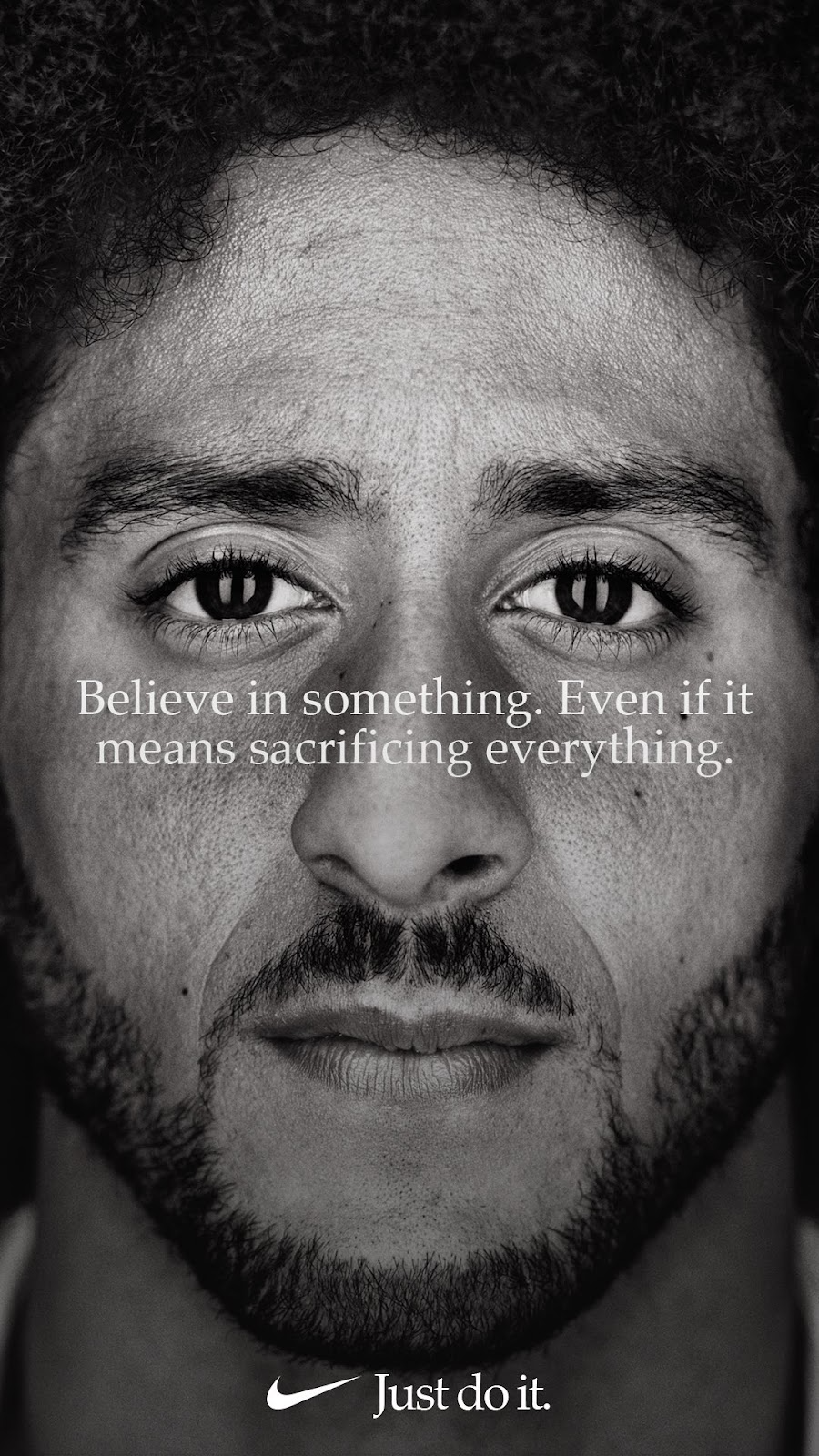 The image from the Colin Kaepernick "Just Do it" campaign. It features a shot of Colin's face looking at the camera with the words "Believe in something. Even if it means sacraficing everything." overlayed on top in white font.