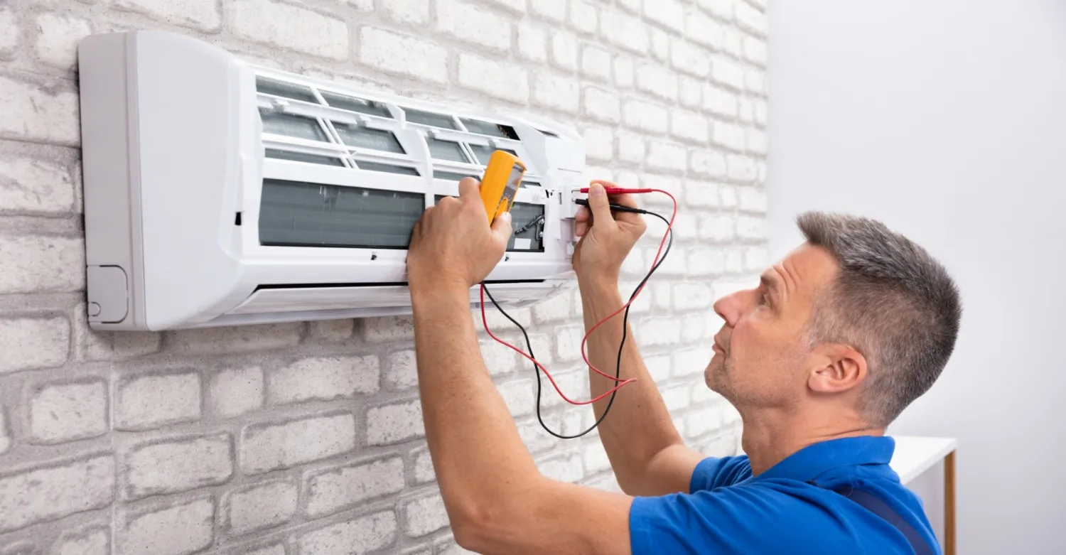 Technician tests split AC unit electrics.