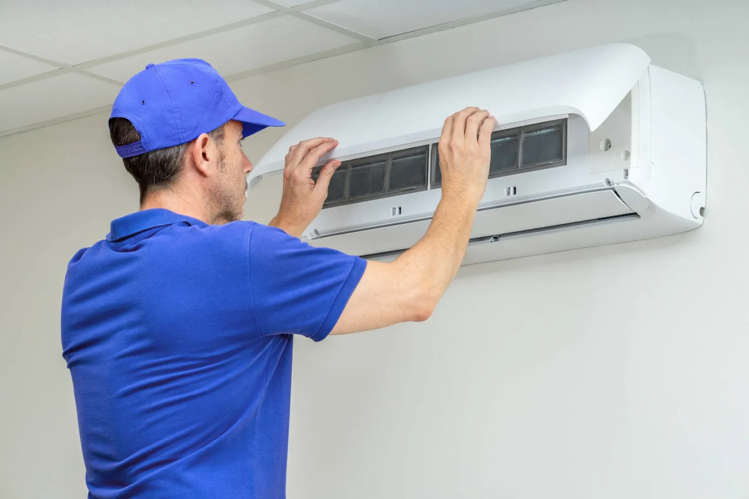 Technician installs or repairs wall AC unit.