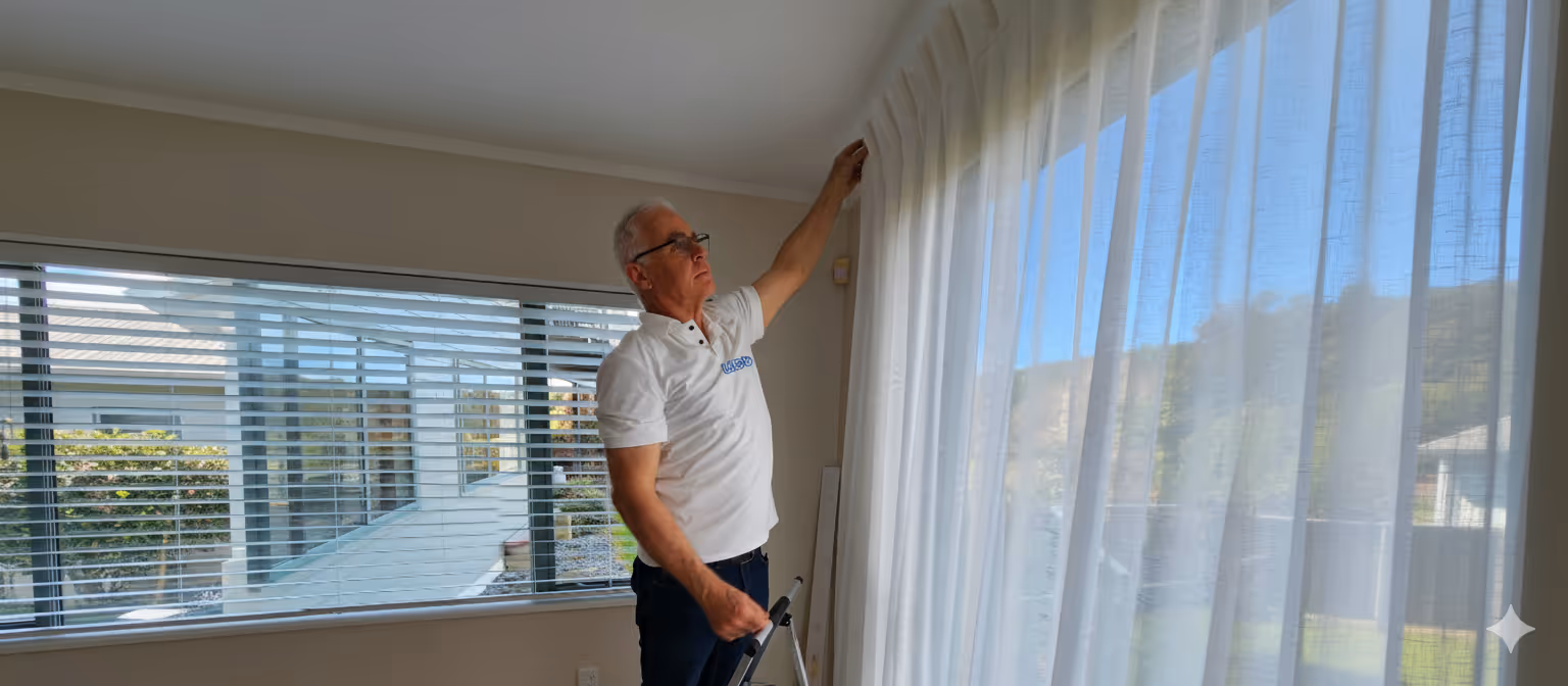 Man installing curtain on step ladder. 