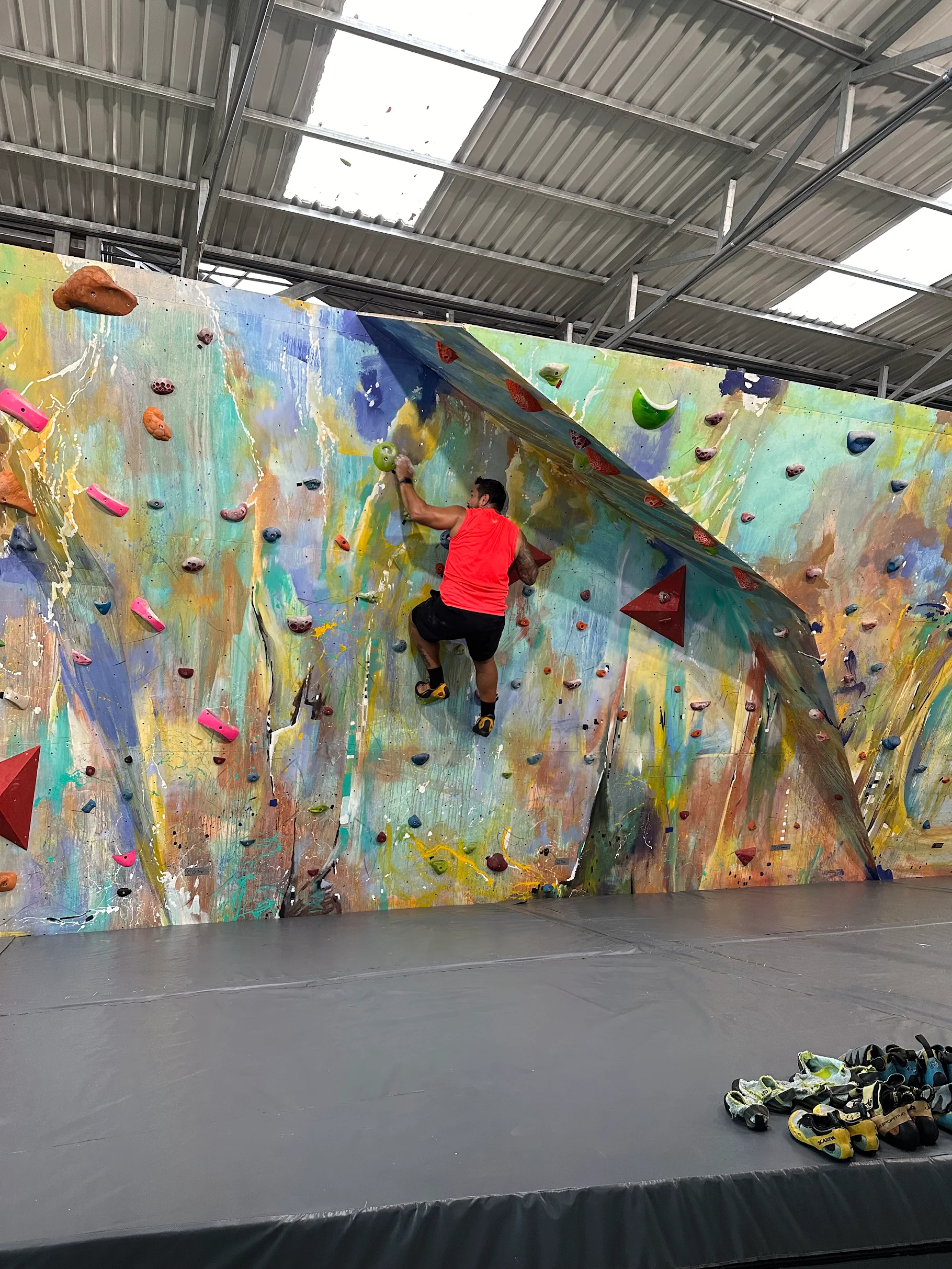 Hombre escalando pared boulder interior en el gimnasio RCCR.