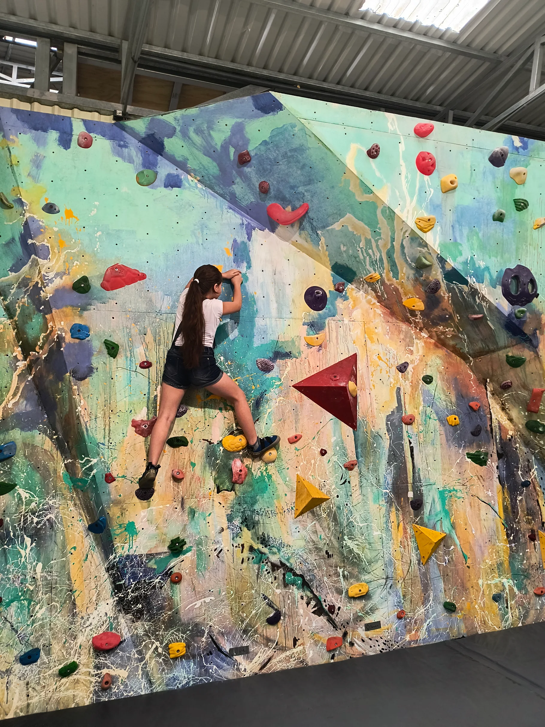 Niña escalando pared boulder interior en el gimnasio RCCR.