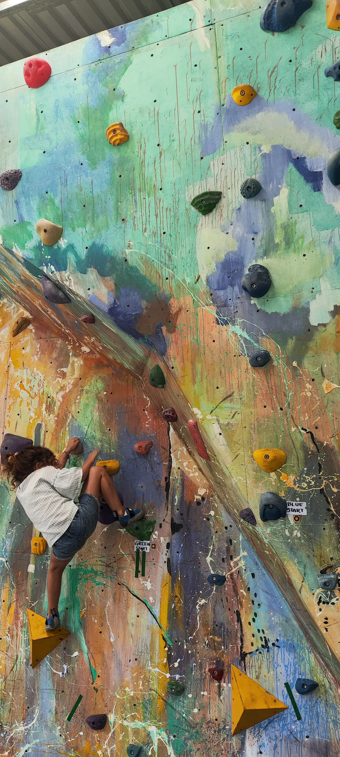 Niño escalando pared boulder interior en el gimnasio RCCR.