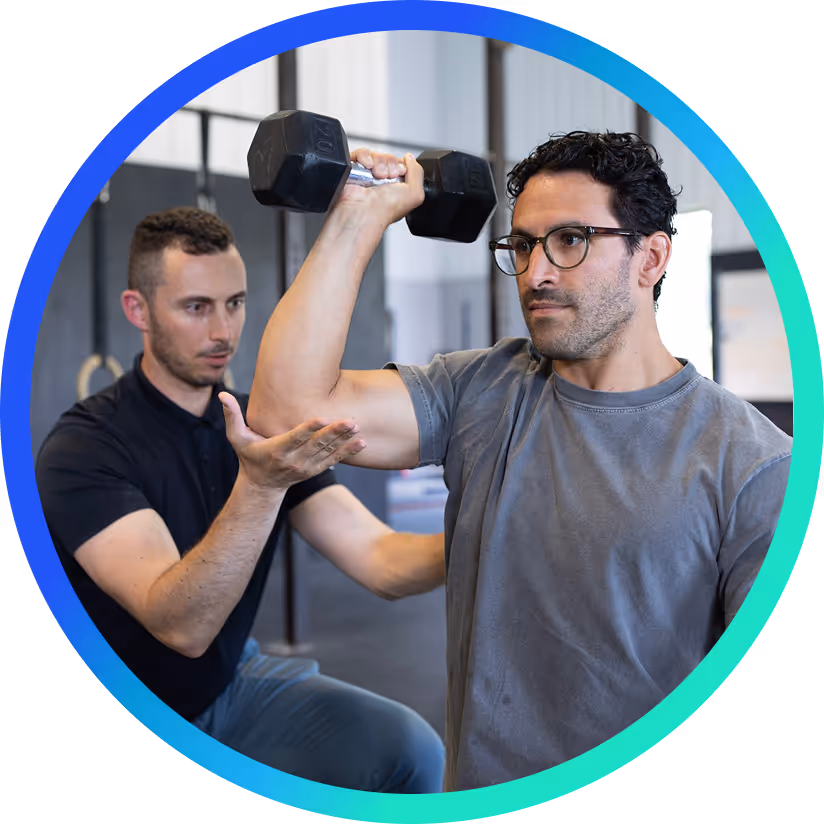 Eric working with a patient, helping them lift a dumbbell