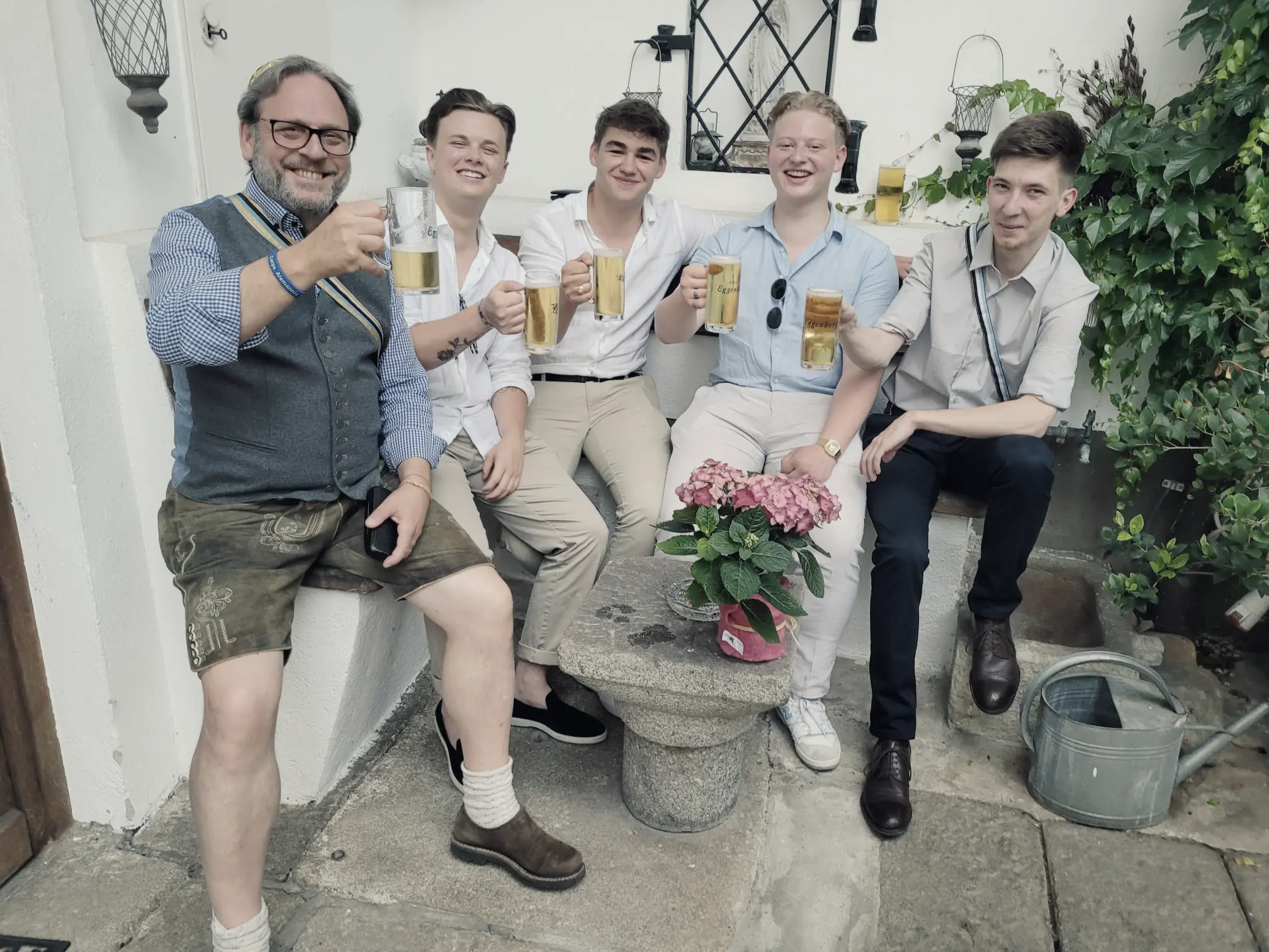 Junge Corps-Studenten stoßen mit einem "Alten Herren" in fröhlicher Runde an.