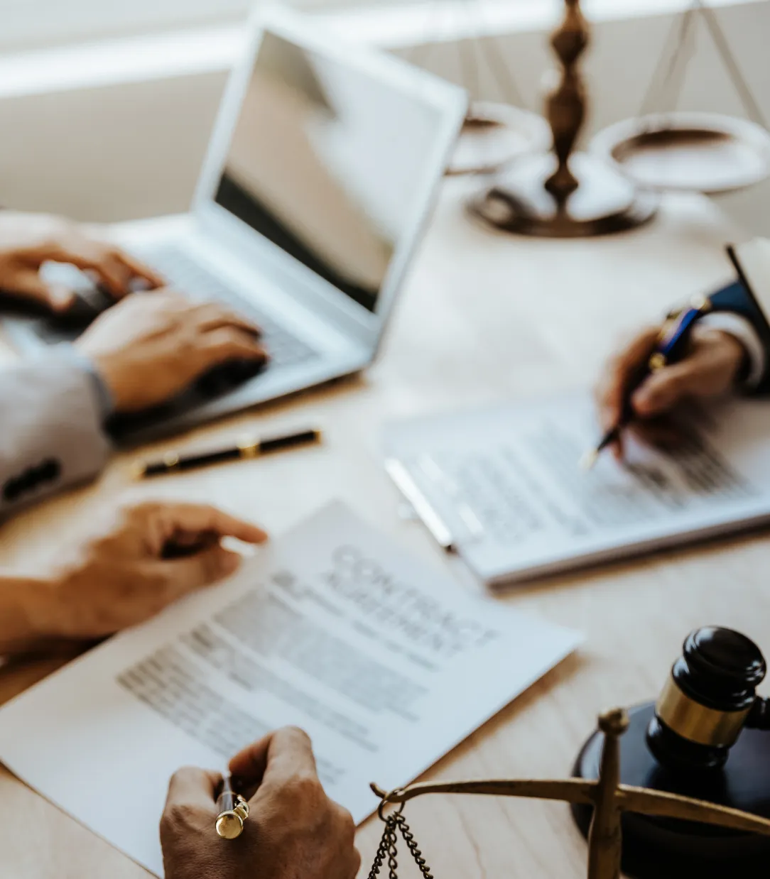 A close up of a team of hands working on a desk with a computer and documents