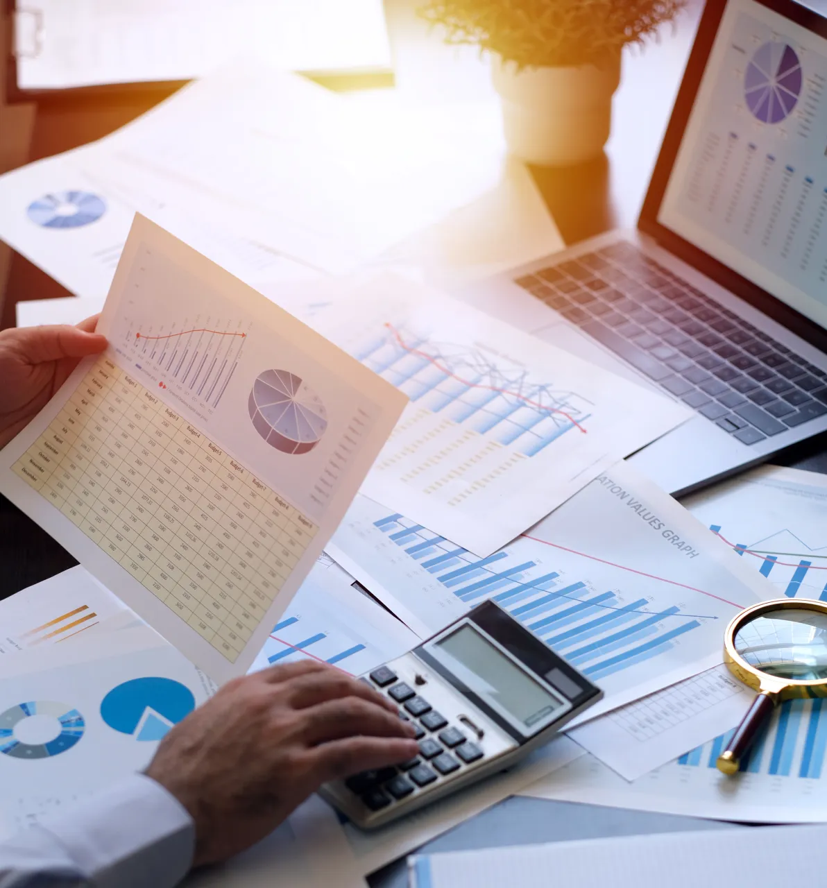 A close up of a business persons handing holding a document why typing on a calculator