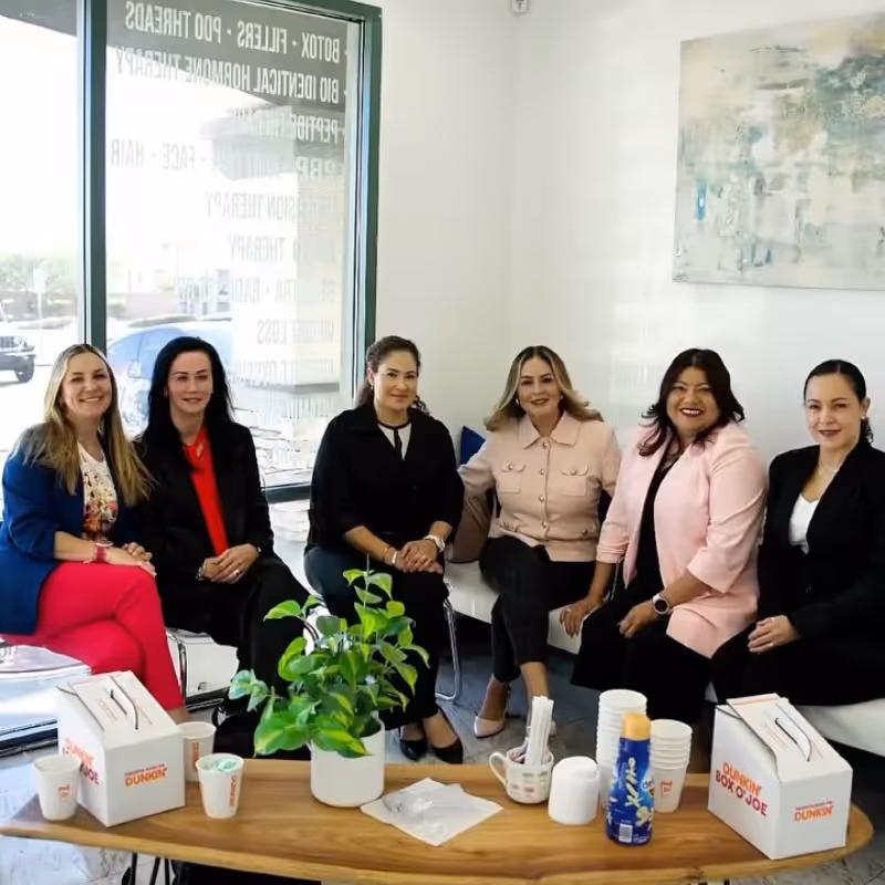 Three smiling medical professionals wearing white lab coats standing in front of a wooden wall with a blue sign reading 'MODERN'.