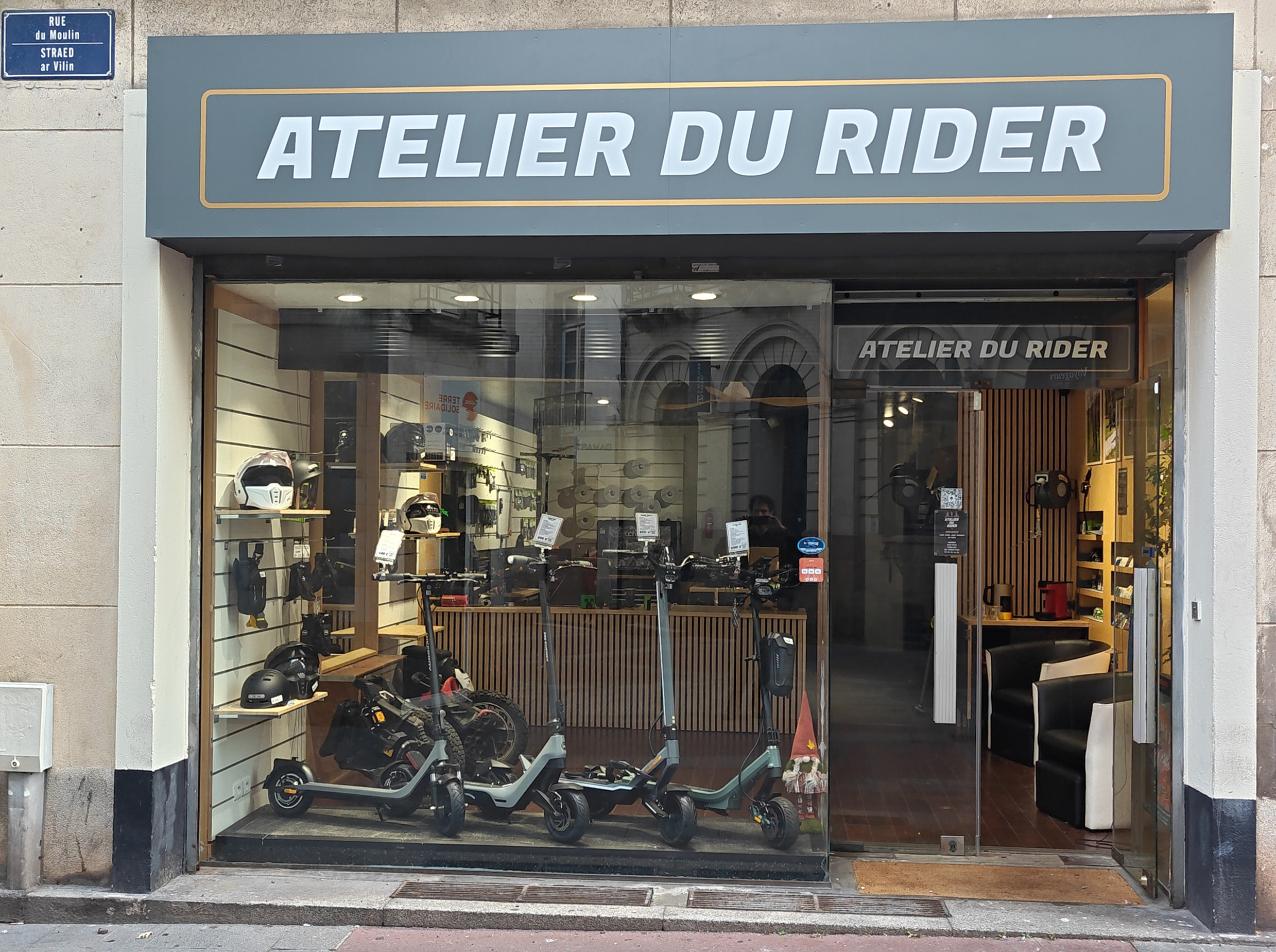 Notre vitrine, située rue du Moulin en plein centre de Nantes, présente directement l’univers de l’atelier : trottinettes électriques, gyroroues, casques et accessoires. Grâce à sa baie vitrée ouverte sur l’intérieur, vous apercevez un espace organisé, moderne et accueillant, mêlant zone d’exposition, comptoir de service et coin détente. Une façade claire et professionnelle qui reflète notre engagement : expertise, proximité et transparence.