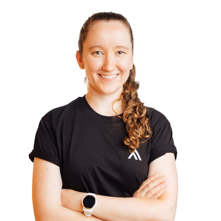 Smiling woman with curly hair tied back, wearing a black t-shirt and a white smartwatch with arms crossed.