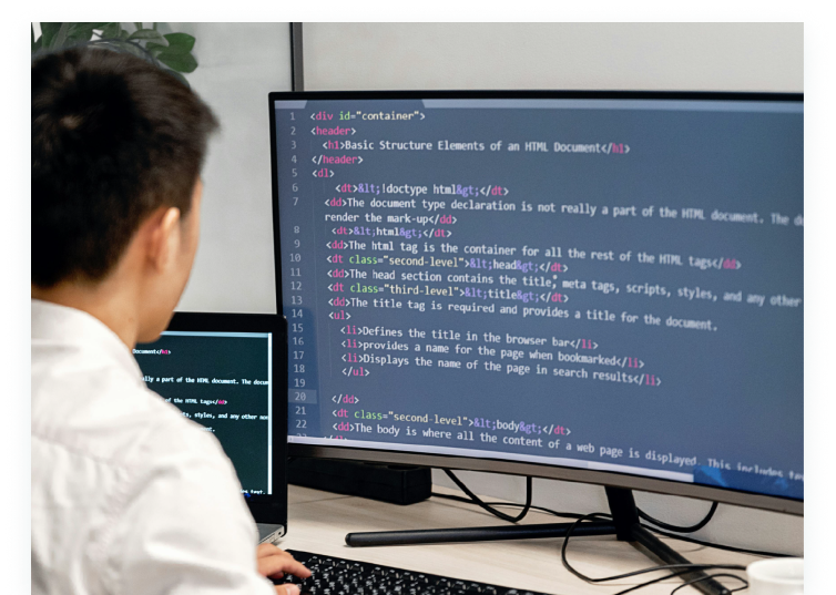Young engineer coding on dual monitors in an office, representing TrackJob’s AI-driven platform for identifying and hiring top fresh graduate engineers in Japan.