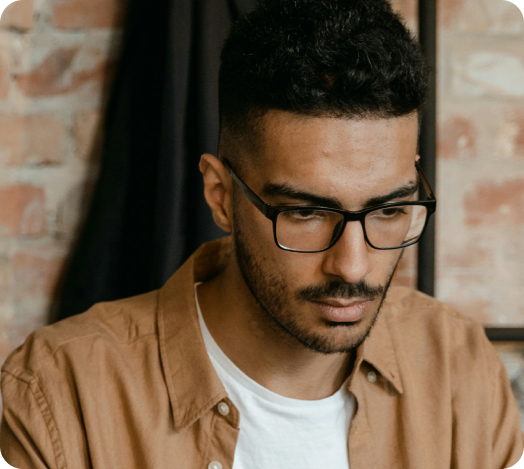 Male professional wearing glasses working at a modern office desk, representing Givery’s global engineering team.