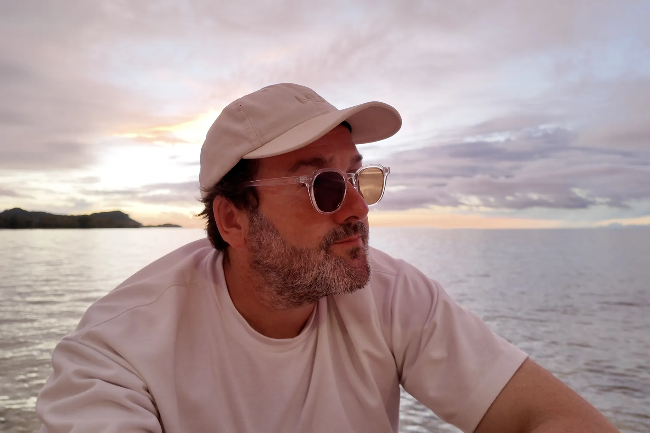 A man wearing a hat and sunglasses on a boat.