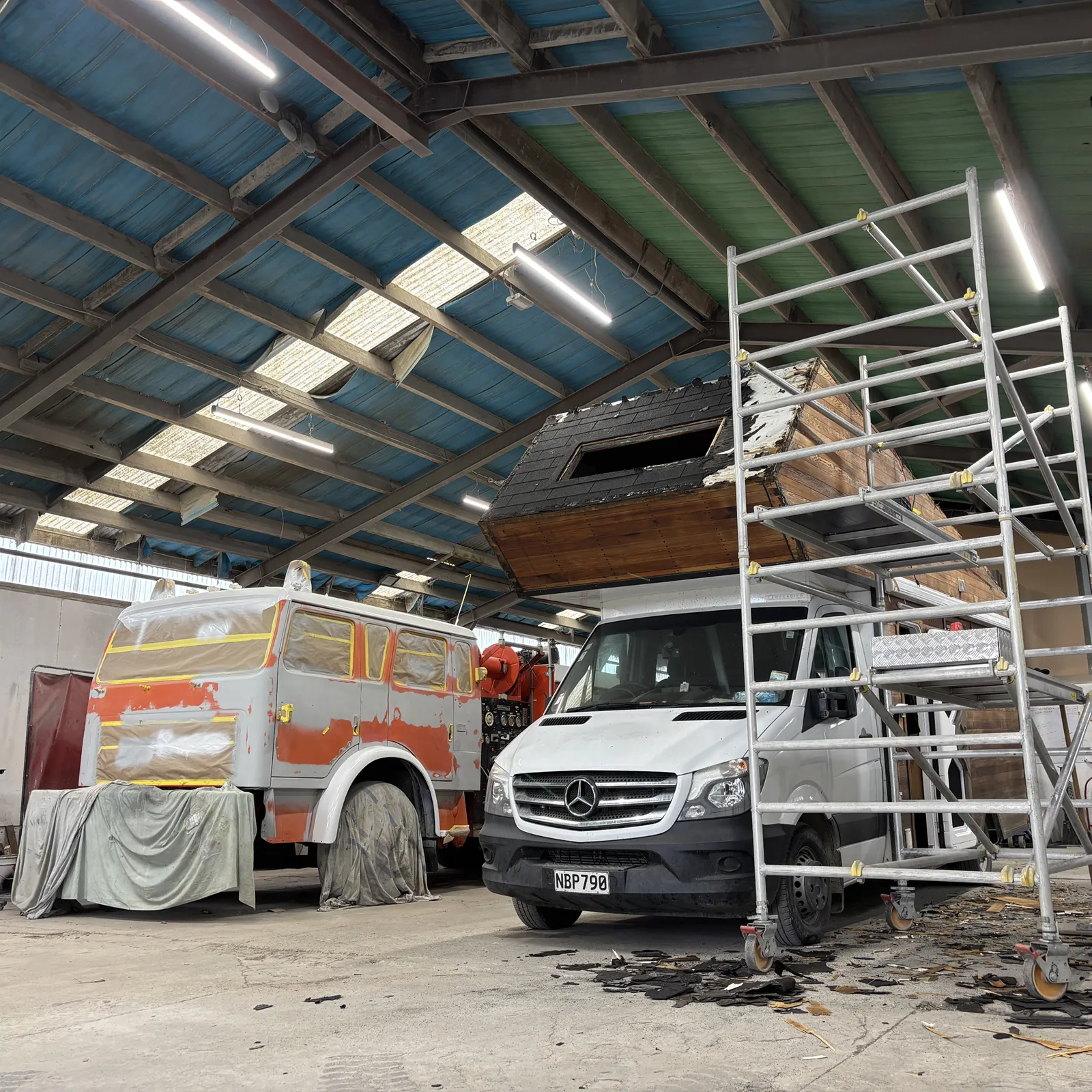 A photo of a firetruck and a motorhome being working on in the BF Motorbodys garage.