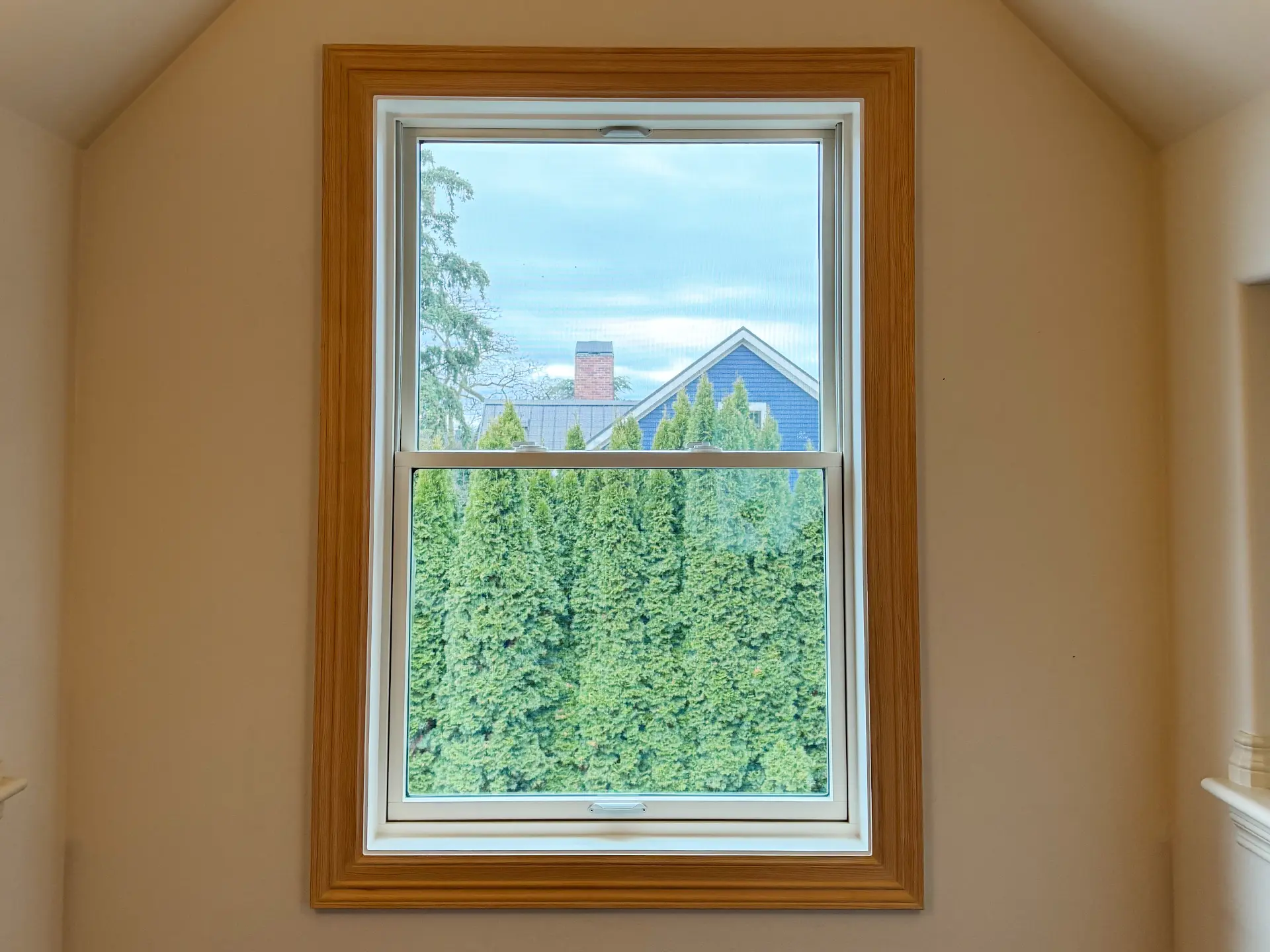 White vinyl replacement window with natural wood interior trim in a Seattle-area home