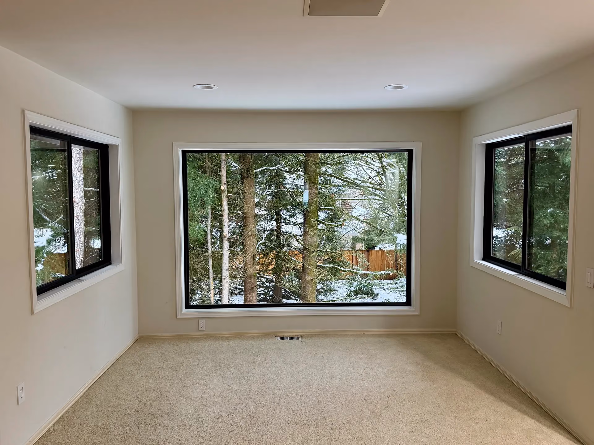 Black-framed replacement windows installed in a bright Seattle-area room