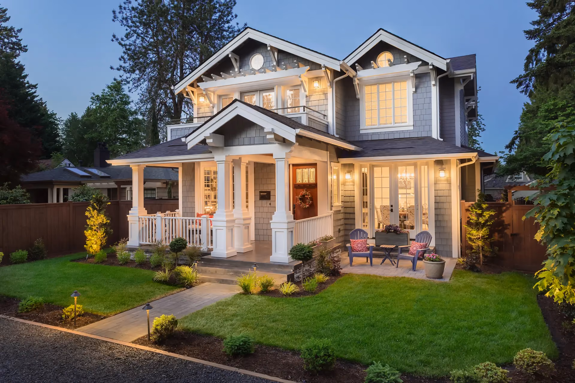 Two-story home with large windows illuminated at dusk