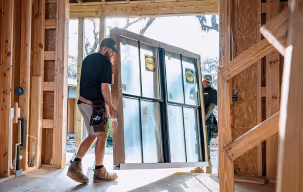 A man stands in front of a partially constructed door, observing the building process.